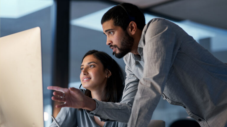 Man and woman pointing at monitor