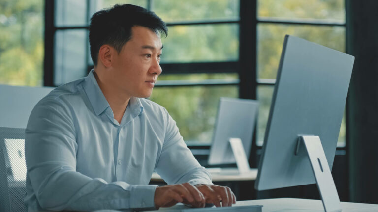 Man working on computer in front of windows