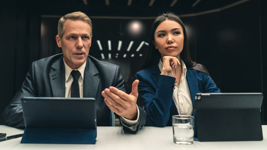 Business man and woman in front of iPads at conference table