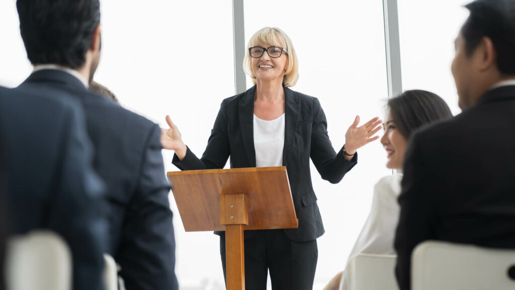 Business woman giving talk in front of lectern